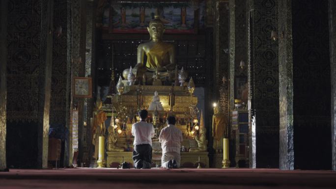 游客在老挝琅勃拉邦寺庙里拜佛