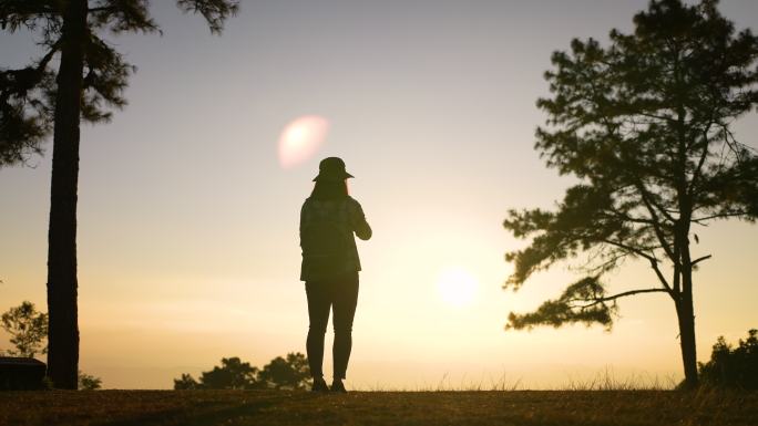 女旅行者在山上日落的美妙地方拍照