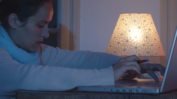 女子夜晚在家使用笔记本电脑