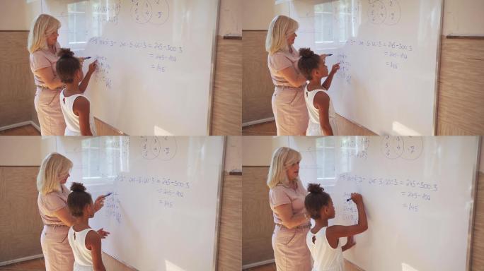小学女生和老师在白板上做数学