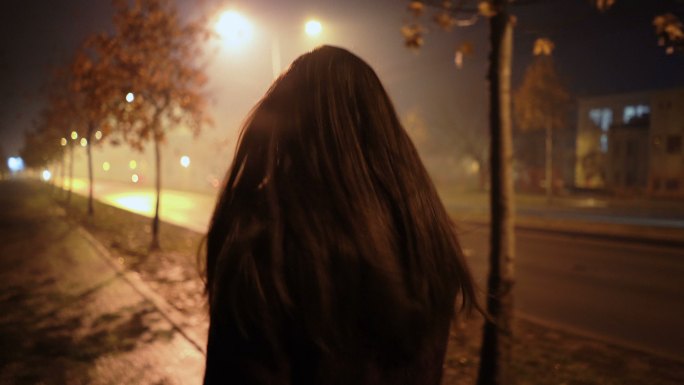 在一个雾蒙蒙的夜晚年轻女子在街上走着