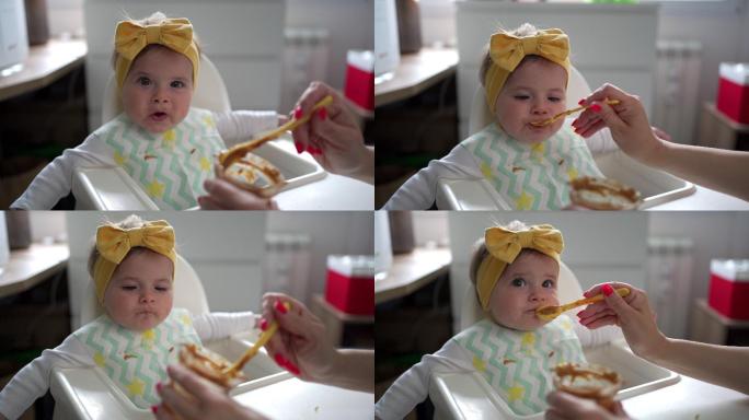 可爱的小女孩在妈妈用勺子喂食物