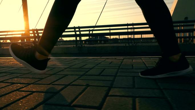在有阳光的桥上行走的人的腿的特写