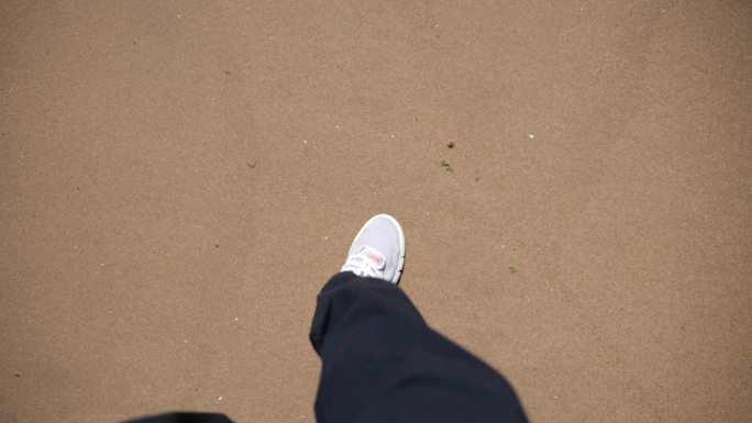 行走在沙滩上脚步鞋黑裤子