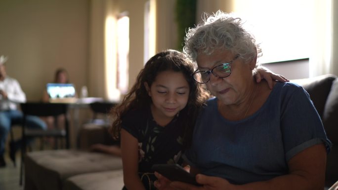 祖母和孙女在家使用手机