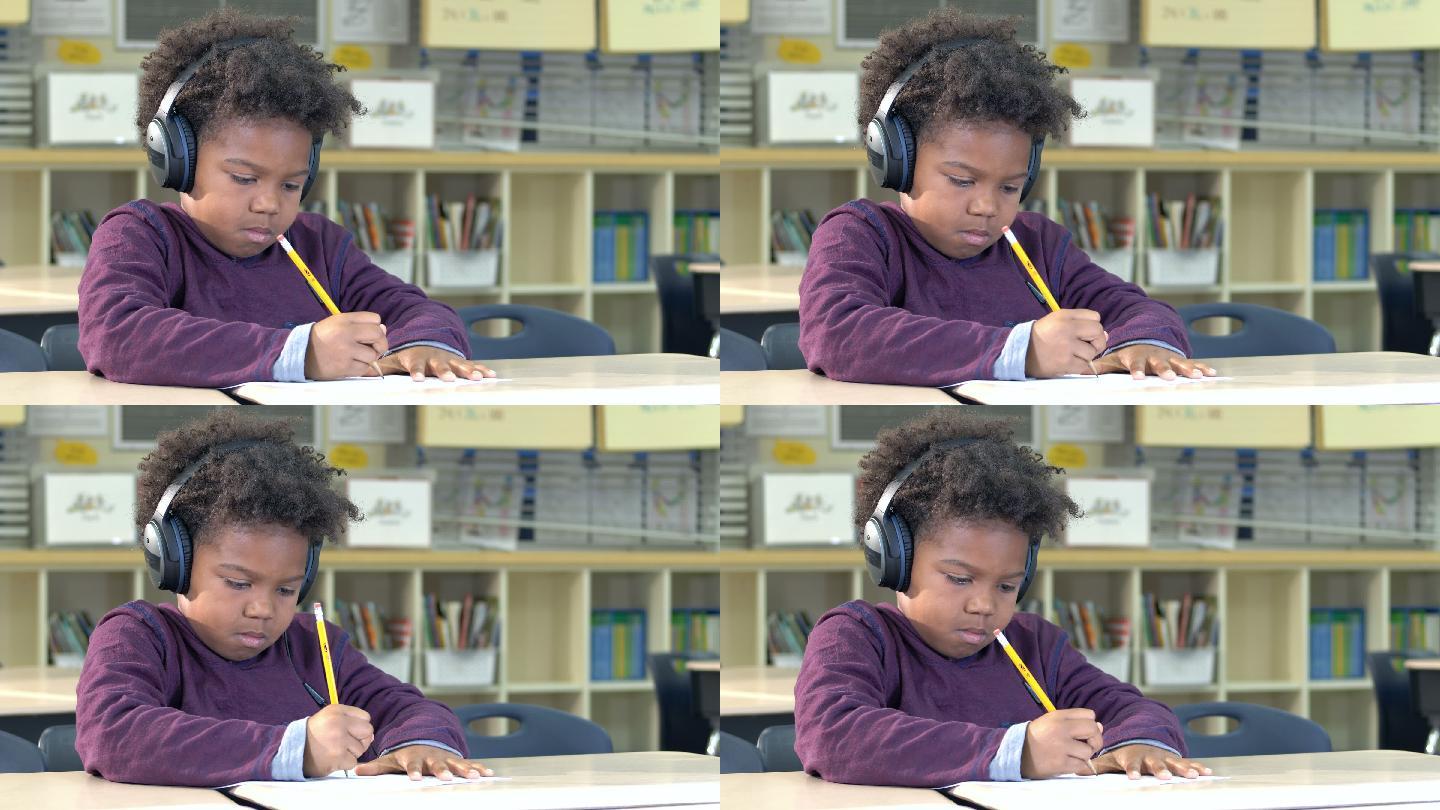 小学生戴着耳机在课堂上写作