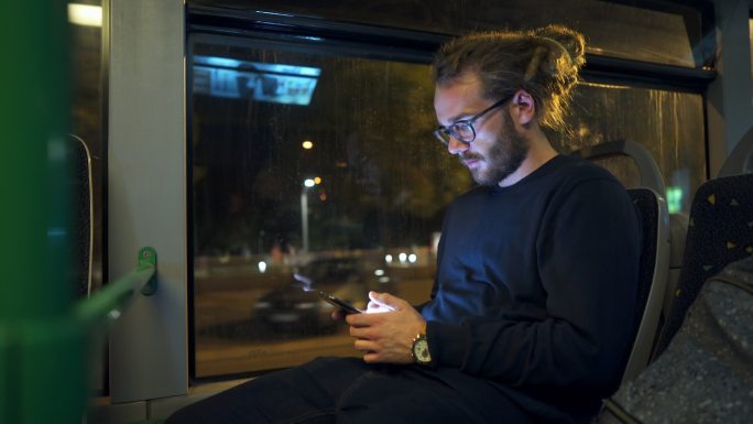 在公共汽车上使用手机的男子