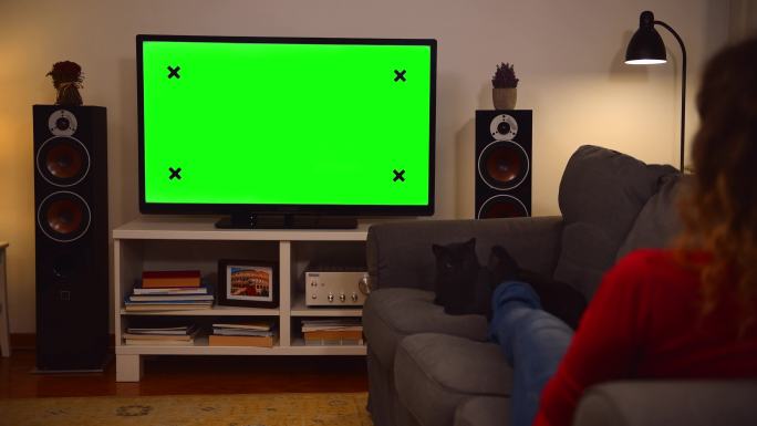 妇女在家看彩色键绿色屏幕电视