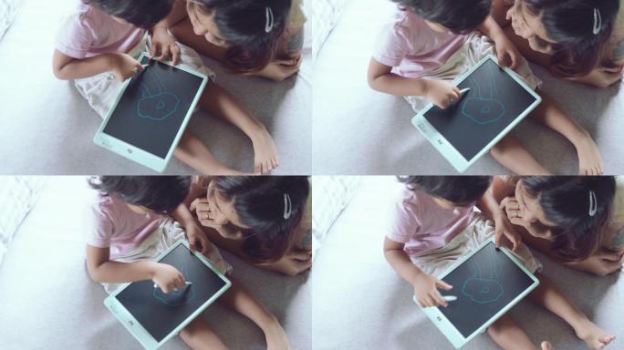 孩子坐在床上用数码板画画。