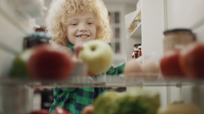 打开冰箱拿水果的小男孩
