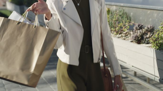 一名年轻女子提着购物袋走在外面