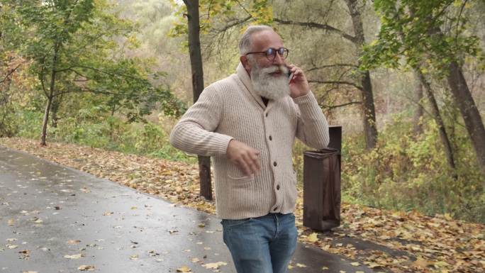 一位老人一边走路一边打电话。