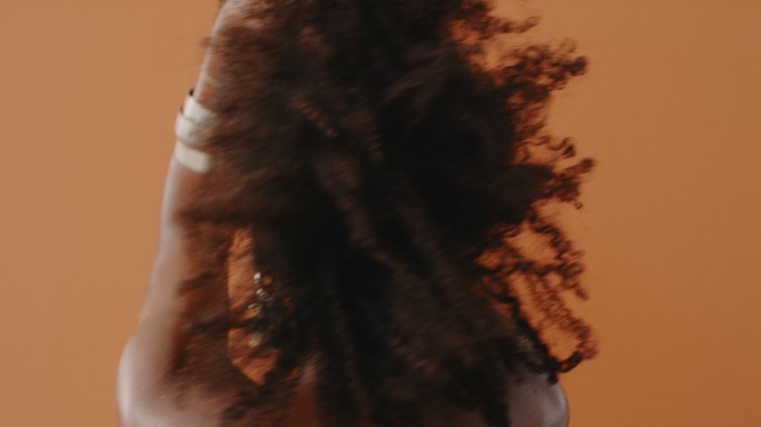 一名卷发女子在棕色背景下跳舞