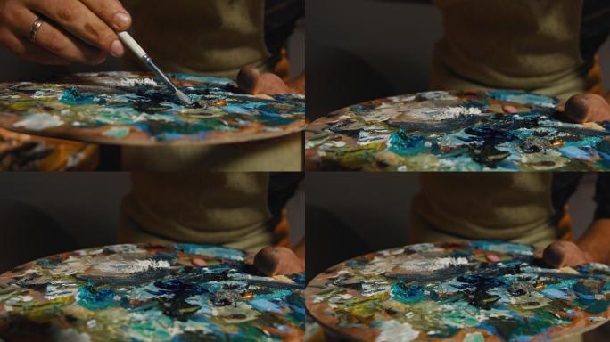 画家正在用画笔从调色板上取颜色画画