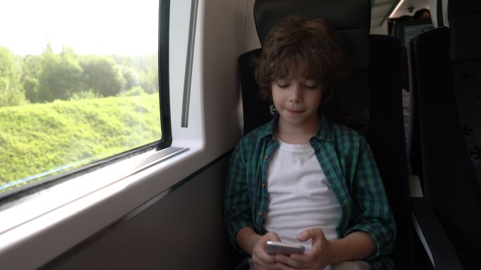 快乐的小男孩在火车上玩手机游戏