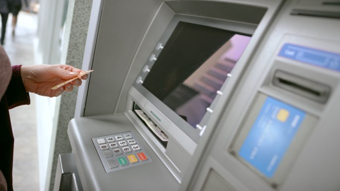 女士从ATM机中取出银行卡和钱，然后走开