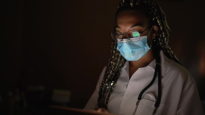 使用数字平板电脑拍摄带口罩的女医生肖像