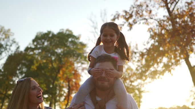 父亲肩上扛着女儿，女儿蒙着眼睛
