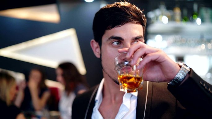 优雅的男人在酒吧里喝威士忌