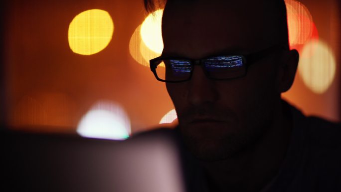 戴着眼镜在笔记本电脑上工作的男人