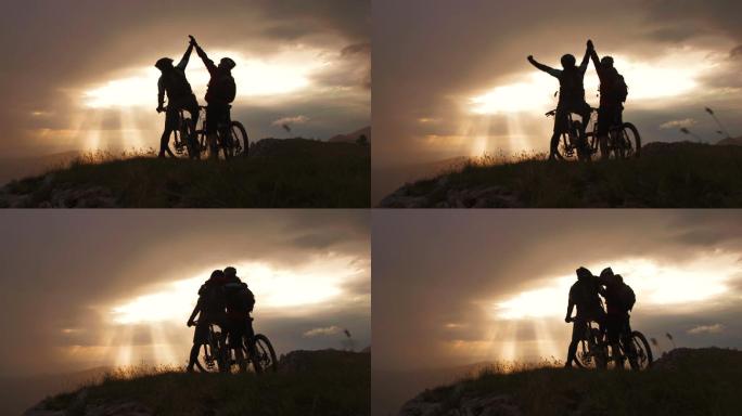 两位山地自行车手的剪影庆祝征服这座山