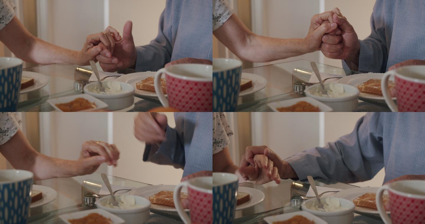 一对夫妇手牵手一起吃早餐的侧视图