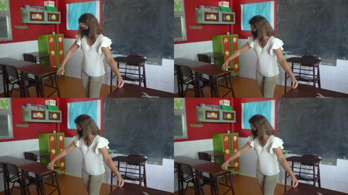 女教师在教室里测量课桌之间的距离