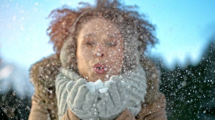 女人把雪吹向空中吹雪浪漫唯美冬季活动穿的