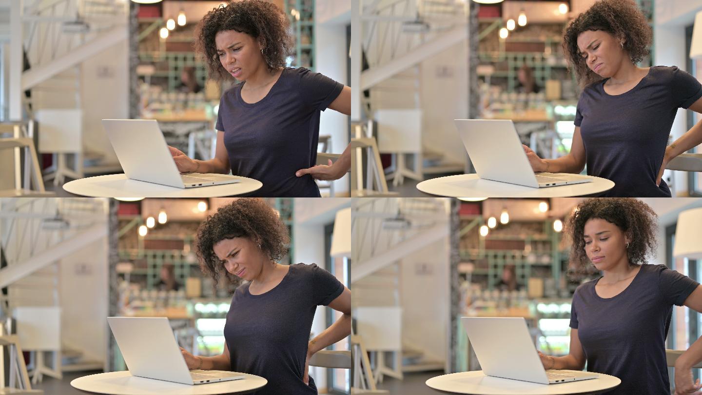 年轻女性背痛时在咖啡馆使用笔记本电脑
