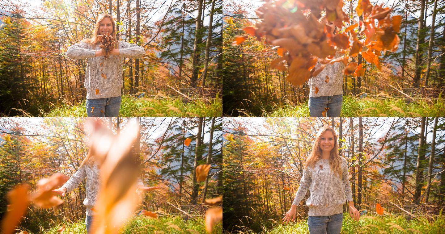 公园里的女人微笑着向镜头扔秋叶