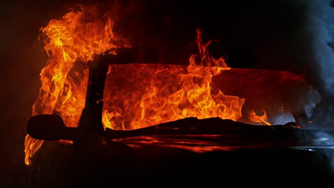 一辆汽车在夜间着火，喷出滚滚火焰