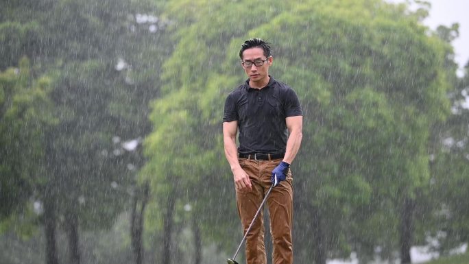 男子高尔夫球手在雨中打高尔夫