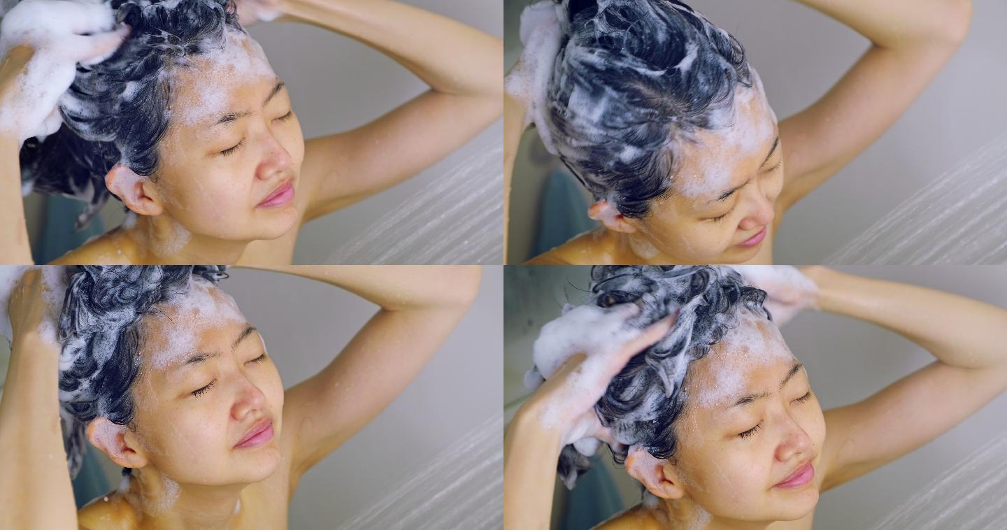 一位年轻的妇女在淋浴时洗头。