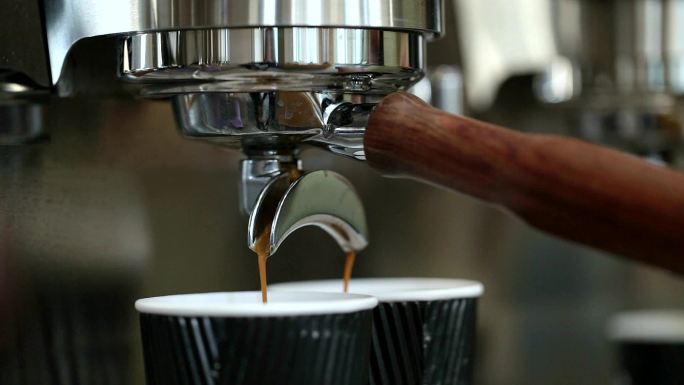 咖啡饮料从咖啡机的过滤口倒入一次性纸杯。