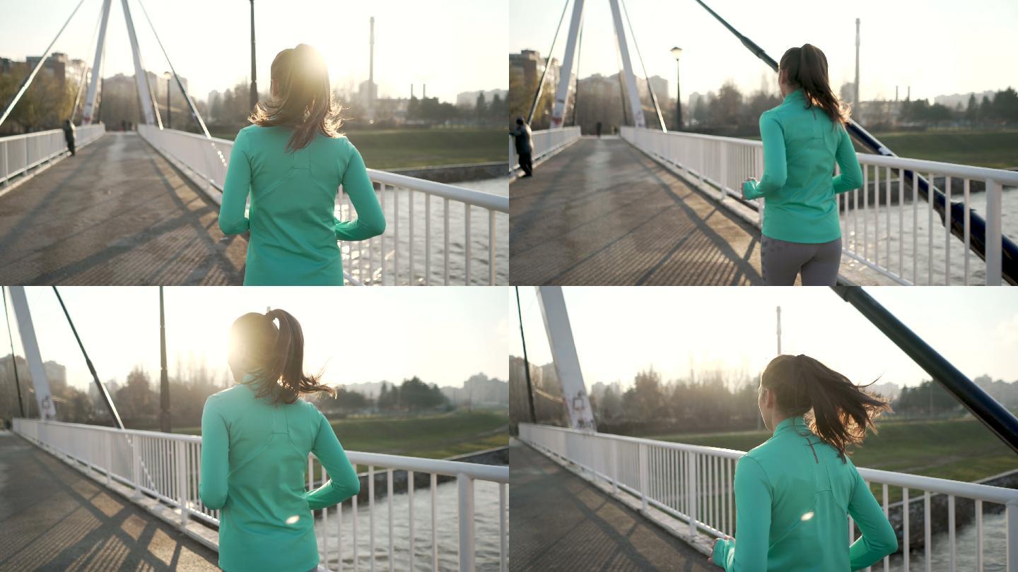 一名年轻女子慢跑过桥的后视图。