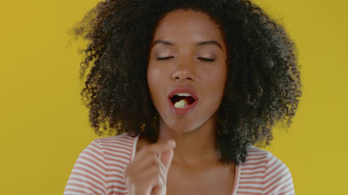 一个女子在黄色背景下吃着苦味的树胶