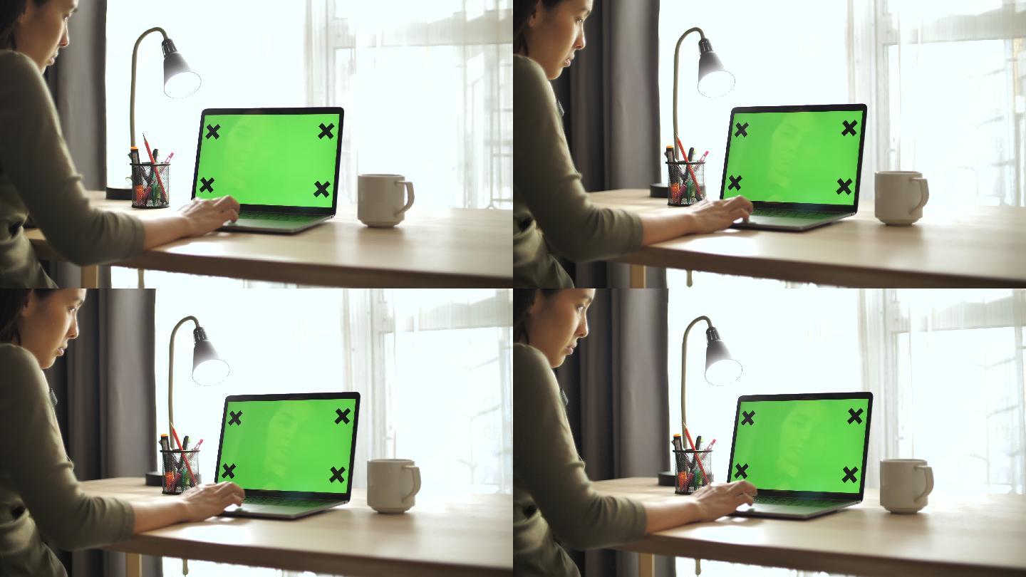 妇女在家使用绿屏笔记本电脑