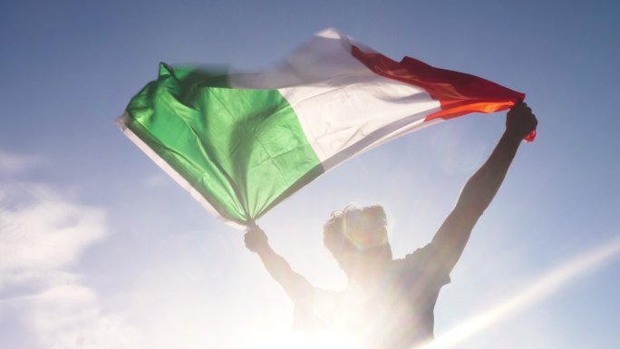 一个年轻人双手举着意大利国旗