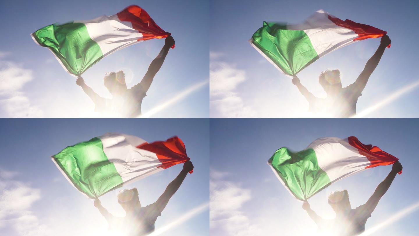 一个年轻人双手举着意大利国旗