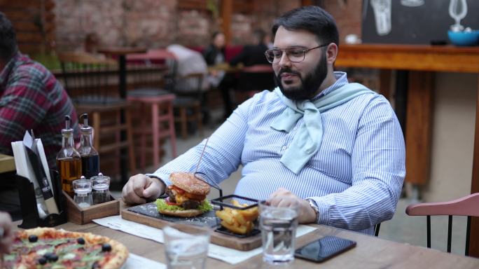超重男子与女友在户外美食酒吧约会时吃东西
