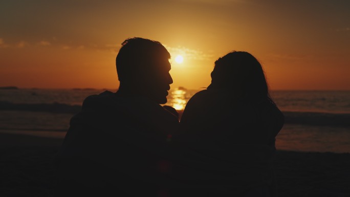 坐在海滩上的夫妇剪影逆光夕阳情侣夫妻