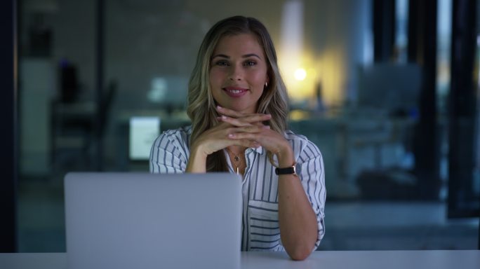 一位年轻女商人在上晚班时使用笔记本电脑
