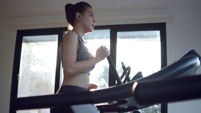 年轻女子在健身房跑步机上跑步