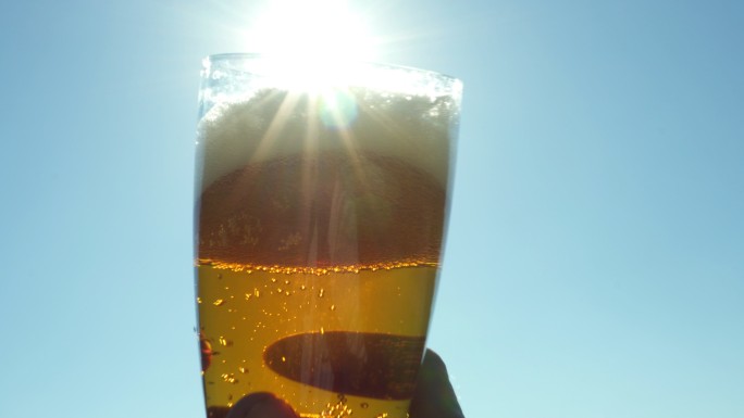 在阳光下手拿一杯啤酒