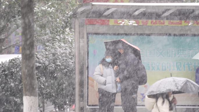 下雪天情侣在公交站等车