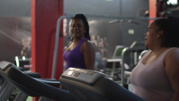 在健身房跑步机上交谈的女性