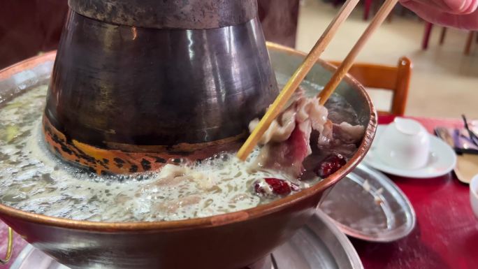 一个人在吃滚烫的老北京涮羊肉，铜锅涮肉