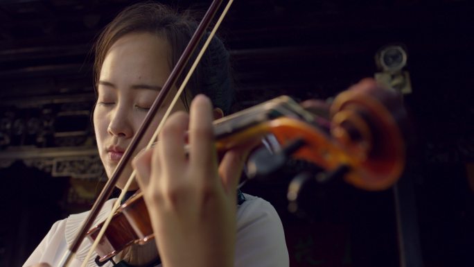 女孩在古老的院子里拉小提琴