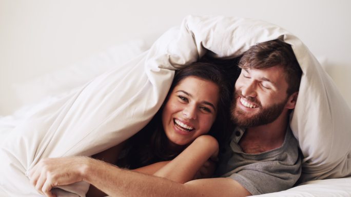 一对幸福的夫妇在家用毯子盖住自己