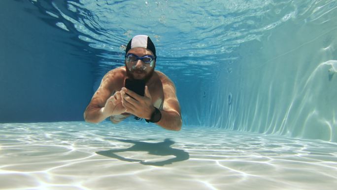 男子在游泳池里使用智能手机